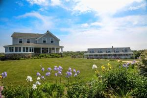 a house on a lawn with flowers in the foreground at Rose Farm Inn in New Shoreham