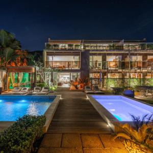 uma casa com piscina à noite em Hotel Spa Nau Royal em Camburi