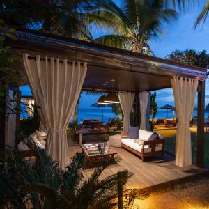 an outdoor patio with curtains and a couch at Hotel Spa Nau Royal in Camburi