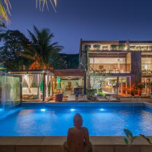 a person sitting in front of a swimming pool at Hotel Spa Nau Royal in Camburi