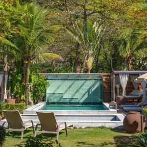 a swimming pool in a yard with chairs and palm trees at Hotel Spa Nau Royal in Camburi