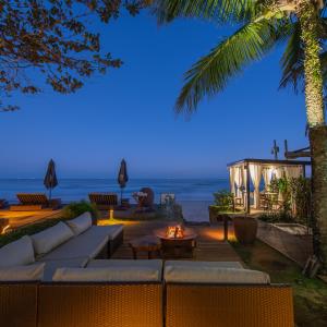 a patio with a fire pit and the beach at night at Hotel Spa Nau Royal in Camburi