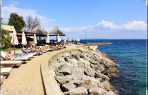 a group of people sitting on a beach near the water at Apartmani Matija in Opatija