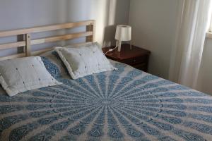 コスタ・ダ・カパリカにあるApartamento Belicheのベッド(青と白の掛け布団、枕付)