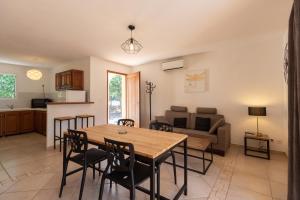 cocina y sala de estar con mesa de madera y sillas en Résidence Spelonca, en Corbara