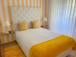 um quarto com uma grande cama branca com lençóis amarelos em Duarte Houses T2 - com vista mar em Nazaré