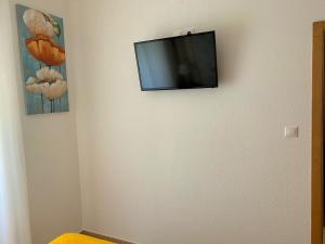 TV de pantalla plana colgada en la pared en Duarte Houses T2 - com vista mar, en Nazaré