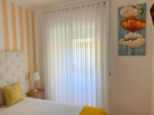 1 dormitorio con 1 cama y una ventana con cortinas blancas en Duarte Houses T2 - com vista mar, en Nazaré