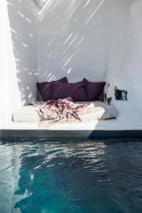 a bed sitting next to a body of water at The Vasilicos in Imerovigli