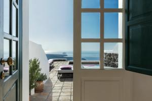 a door leading to a balcony with a view of the ocean at The Vasilicos in Imerovigli