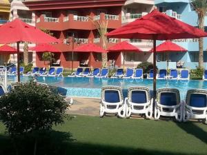 a group of chairs and umbrellas next to a pool at شاليهات بورتو ساوث بيتش للأسر فقط An in Ain Sokhna