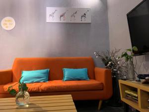 un sofá naranja con 2 almohadas azules en una habitación en Monkey Safari Hostel, en Querétaro