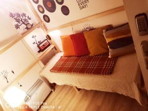 a small bedroom with a bed with colorful pillows at Pijama Hostel in Plovdiv