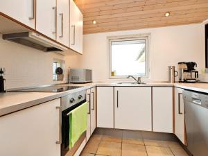 a kitchen with white cabinets and a window at 7 person holiday home in R dby in Rødby