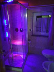 La salle de bains est pourvue d'une douche avec des lumières violettes. dans l'établissement casa claudio-APPARTAMENTI IN CENTRO, à Campitello di Fassa