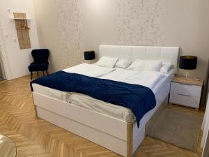 1 dormitorio con cama blanca y manta azul en W19 Apartments, en Miskolc