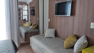a room with a couch and a television on a wall at Apart Hotel Pedra Azul in Pedra Azul