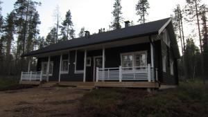 uma casa negra com um alpendre na floresta em Vanamo em Ylläsjärvi