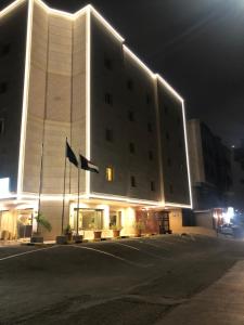 un bâtiment avec drapeaux devant lui la nuit dans l'établissement Dar Al Maamon Furnished Apartment, à Djeddah