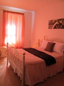 a bedroom with a bed with pink walls and a window at Casa Das Lages in Alvoco da Serra
