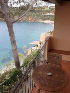 una mesa de madera y una silla en un balcón con vistas al océano en Rosa dei Venti en Capoliveri
