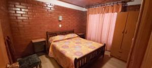 Dormitorio pequeño con cama y pared de ladrillo en Cabaña Pizarro Horcón, en Horcón