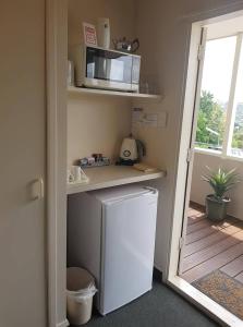 Il comprend une petite cuisine équipée d'un réfrigérateur blanc et d'un four micro-ondes. dans l'établissement Panorama Motor Inn, à Te Kuiti