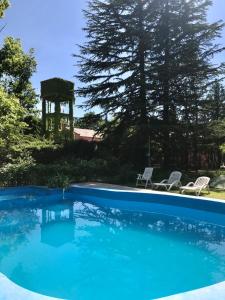 una piscina azul con 2 sillas y un cenador en La Danesa en Luján de Cuyo