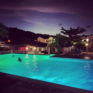 una piscina por la noche con gente nadando en ella en Superbe studio de standing à 800m de la mer des Caraïbes le hameau de beauregard sainte anne en Sainte-Anne