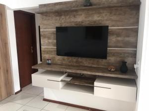 un centro de entretenimiento con TV en la pared en Residencial la bela praia, en Florianópolis