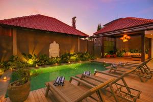 a resort with a swimming pool with chairs and a house at Uwu Villas in Canggu