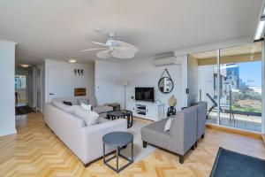 ein Wohnzimmer mit einem Sofa, Stühlen und einem TV in der Unterkunft Dorchester On The Beach in Gold Coast