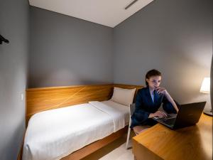a woman sitting on a bed with a laptop at The Bed KLCC in Kuala Lumpur