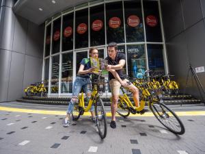 two men riding bikes in front of a building at The Bed KLCC in Kuala Lumpur