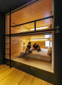two people sitting on a bunk bed in a room at The Bed KLCC in Kuala Lumpur