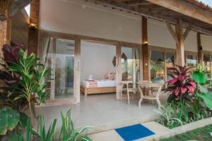 een veranda van een huis met een tafel en een bed bij Peaceful Haven 6BR Private Pool Villa in Canggu in Canggu