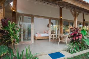 eine Veranda eines Hauses mit einem Tisch und einem Bett in der Unterkunft Peaceful Haven 6BR Private Pool Villa in Canggu in Canggu