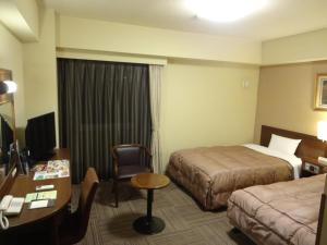 防府市にあるホテル ルートイン 防府駅前のベッド2台とデスクが備わるホテルルームです。