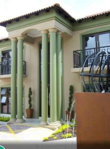 a building with green columns in front of a building at Royal Hotel in Polokwane