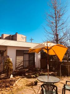 une table avec un parasol devant une maison dans l'établissement K's House MtFuji -ケイズハウスMt富士- Travelers Hostel- Lake Kawaguchiko, à Fujikawaguchiko
