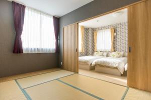 ein Schlafzimmer mit einer Tür, die zu einem Schlafzimmer mit 2 Betten führt in der Unterkunft guest house Sora in Osaka