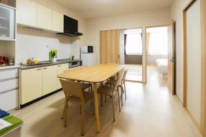 Il comprend une cuisine et une salle à manger avec une table et des chaises en bois. dans l'établissement guest house Sora, à Osaka