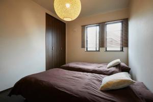 sypialnia z łóżkiem i 2 oknami w obiekcie Chie's house w mieście Mitaka