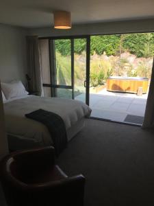 a bedroom with a bed and a view of a yard at The Black House with Stunning Outdoor Bath in Lake Tekapo