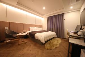 a bedroom with a bed and a table and a chair at Den Basta Hotel in Busan