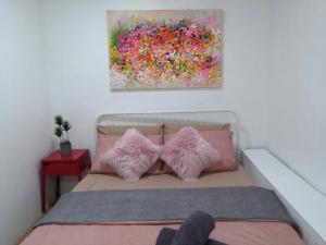 a bedroom with a bed with pink pillows and a painting at Malacca Jonkerhouse in Malacca