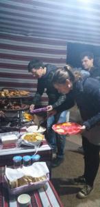 a group of people standing around a table with food at Bronze Mountains Camp Wadi Rum in Wadi Rum +69 photos