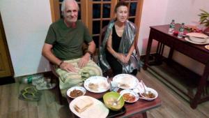 un homme et une femme assis sur une table avec de la nourriture dans l'établissement Cukoos Nest, à Cochin