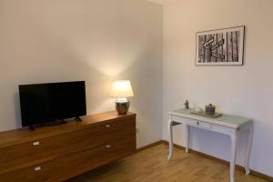 a room with a television on a dresser with a table with a lamp at Appartement Zauner in Oberndorf bei Salzburg