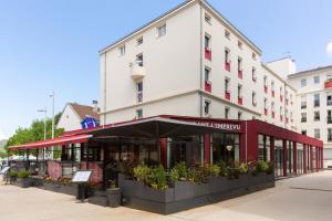 una tienda frente a un edificio con plantas floridas en Hôtel Central Parc Oyonnax, en Oyonnax